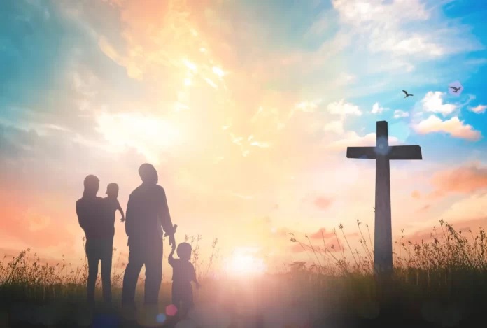 A picture of a christian family standing infront of a cross